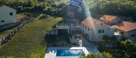 A villa with a swimming pool, stone walls, and a garden.