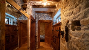 Passadís estret amb parets de pedra, portes de fusta i un paviment de fusta.