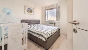 Una camera da letto con un letto, una culla, una finestra con vista e una porta.