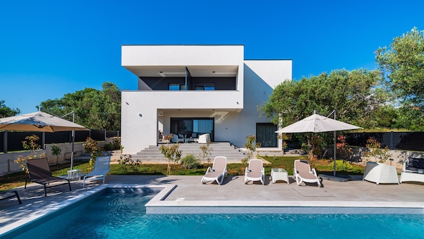 Une maison moderne à deux étages, dotée d’une piscine, d’un espace extérieur aménagé et d’un jardin bien entretenu.