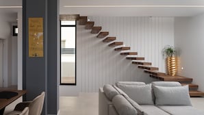 A modern living room with a built-in staircase, a sofa, and a potted plant. - Villa Santa With Heated Pool (Pakostane)