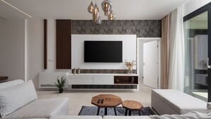 A modern living room with a large flat-screen TV, a sofa, a coffee table, and a sideboard with decorative items. - Villa Santa With Heated Pool (Pakostane)