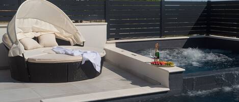 Un espace aménagé au bord de la piscine, avec un fauteuil abrité et une bouteille de champagne.