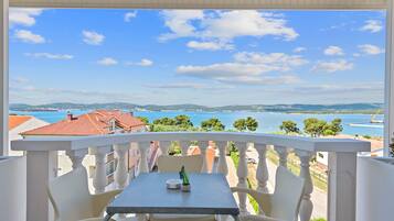 A balcony with a table and chairs, overlooking a scenic view of a body of water and distant hills.