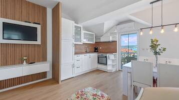 A modern kitchen with a built-in TV, white cabinetry, and a wooden accent wall.