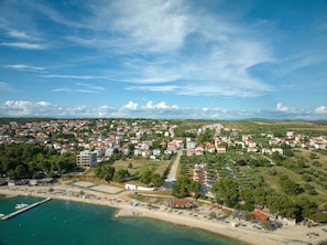 An aerial view of a coastal town with residential buildings, a marina, and a beach area. - Superior Apartment Tania 13 (Sveti Filip i Jakov)