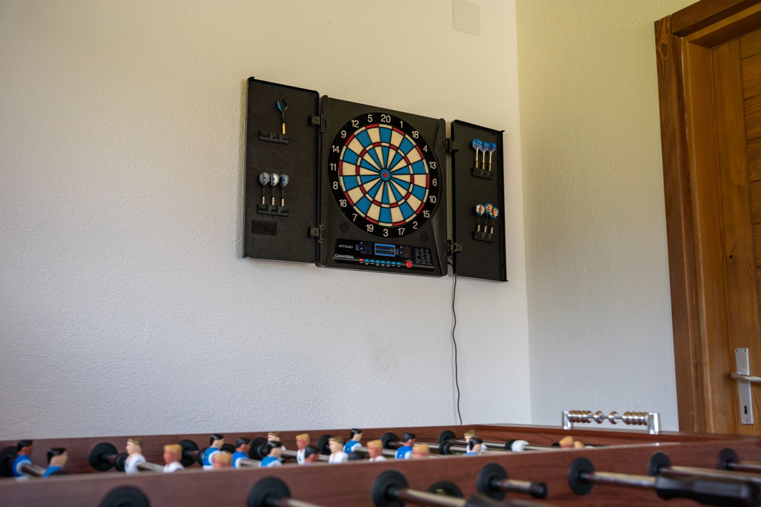Eine Dartscheibe an der Wand, im Vordergrund ein Fußballtisch.