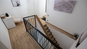 A staircase with wooden steps and a black metal railing, leading to a landing with a white door and a small desk with a plant. - Holiday Home Lantina With Pool (Novigrad)