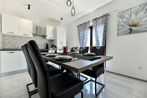 Eine moderne Küche mit weißen Schränken, einem Esstisch mit Geschirr und Gläsern sowie einem großen Blumenbild an der Wand.