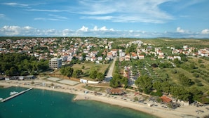 An aerial view of a coastal town with residential buildings, a marina, and a beach area. - Superior Studio Tania 16 (Sveti Filip i Jakov)