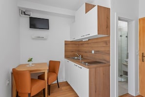 Eine kompakte Küche mit einer Wand in Holzoptik, einer integrierten Spüle und einem Fernseher, der über der Arbeitsfläche angebracht ist.