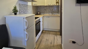 A compact kitchen with white cabinets, a tiled backsplash, and a small stove. - Studio Apartment Nia (Nin)