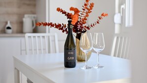 Une table à manger avec une bouteille de vin, deux verres à vin et un vase rempli de fleurs.
