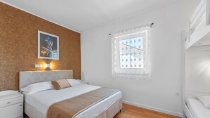 Een slaapkamer met een bed, nachtkastje en een raam met gordijn.