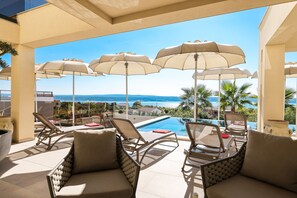 A sunlit outdoor lounge area with multiple lounge chairs and umbrellas, overlooking a pool and a scenic ocean view. - Luxury Villa Nuova With Heated Pool (Jasenice)