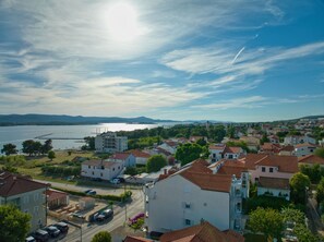 A coastal town with residential buildings, a road, and a body of water. - Superior Studio Tania 12 (Sveti Filip i Jakov)