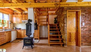 Une cuisine rustique avec des meubles en bois, un poêle noir et un mur en briques.
