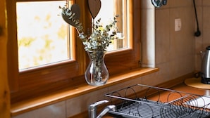 A kitchen with a wooden countertop, a stainless steel sink, a vase with flowers, and a window with lace curtains. - Holiday Home Ventura (Varazdinske Toplice)