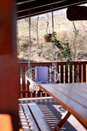 Une terrasse en bois avec un fauteuil suspendu et une table de pique-nique.