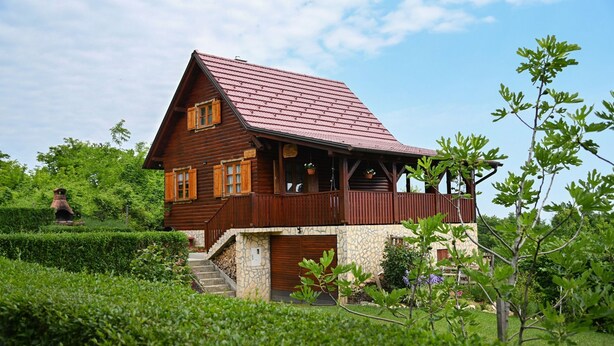 A wooden cabin with a sloped roof, a porch, and a stone foundation. - Holiday Home Ventura (Varazdinske Toplice)