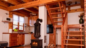 A rustic kitchen with a wood stove, wooden cabinets, and a wooden staircase. - Holiday Home Ventura (Varazdinske Toplice)