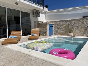 A pool area with lounge chairs, a blue door, and a stone wall. - Holiday Home Cherry With Pool (Marina)