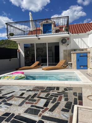A two-story house with a swimming pool, a balcony with a white umbrella, and a stone-tiled patio. - Holiday Home Cherry With Pool (Marina)