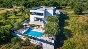 A modern two-story house with a swimming pool, surrounded by lush greenery and a clear sky. - Apartment Vista Mare 2 With Heated Pool (Sveti Filip i Jakov)