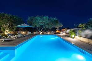 A rectangular swimming pool with a blue tint, surrounded by lounge chairs and an umbrella. - Apartment Vista Mare 2 With Heated Pool (Sveti Filip i Jakov)