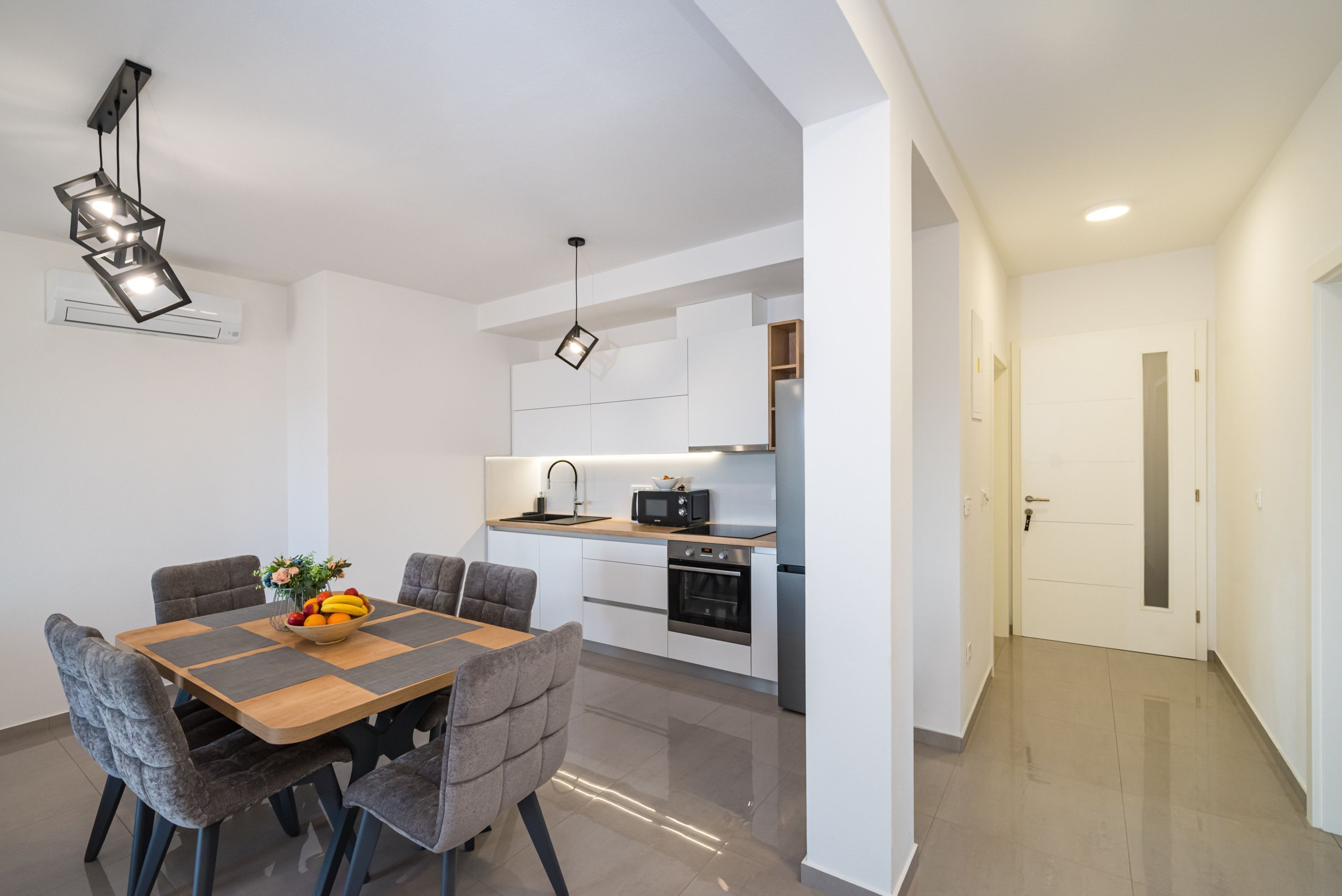 Une cuisine moderne avec des meubles blancs, un four encastré et un micro-ondes.