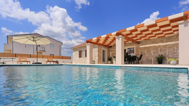 Piscina com pergolado de madeira e espreguiçadeiras.