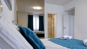 Quarto de hotel com cama, banheiro com chuveiro e porta que dá para outro cômodo.