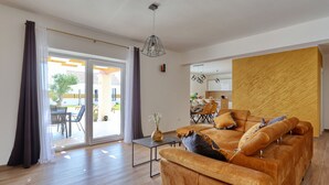 Uma sala moderna com um sofá, uma mesa de centro e uma área de jantar visível através de uma porta de vidro.