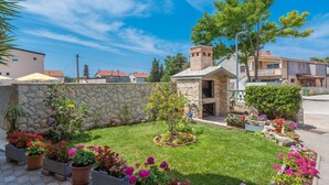 A well-maintained garden with various flowering plants and a stone wall. - Apartment Brevilacqua (Privlaka)