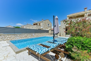 Ein Swimmingpool mit Liegestühlen und einer Steinmauer.