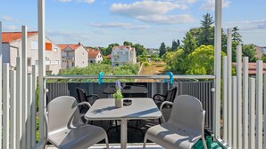 Ein Balkon mit Tisch und Stühlen, der auf einen Wohnbereich mit Häusern und Grünflächen blickt.