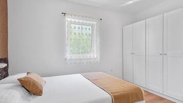 A bedroom with a bed, a window with a curtain, and a wardrobe.
