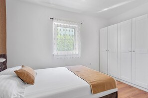 Ein Schlafzimmer mit einem Bett, einem Fenster mit Vorhang und einem Kleiderschrank.