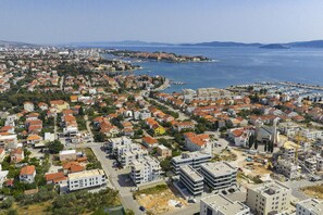 An aerial view of a coastal town with residential buildings, a marina, and a clear view of the sea. - Luxe Apartment Verto (Zadar)