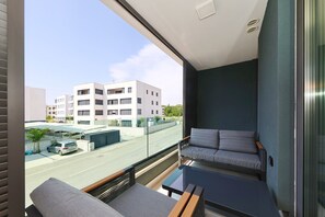 A modern balcony with a sofa and a small table, offering a view of the street and buildings. - Luxe Apartment Verto (Zadar)