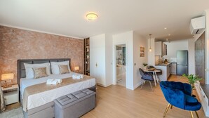 Moderni hotellihuone, jossa on suuri sänky, oleskelualue ja pieni keittiönurkkaus.