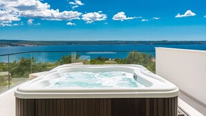 Ett bubbelbad på en balkong med utsikt över en sjö eller ett hav och en klar himmel.