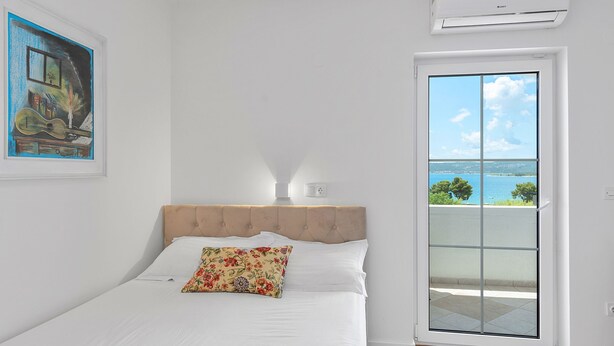 A bedroom with a bed, a window with a view of the sea, and an air conditioning unit. - Superior Studio Tania 7 (Sveti Filip i Jakov)
