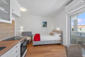A compact bedroom with a bed, bedside table, and a small seating area. - Superior Studio Tania 7 (Sveti Filip i Jakov)