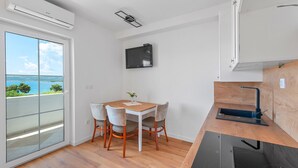 A compact kitchen with a dining area, a built-in TV, and a view of the sea. - Superior Studio Tania 7 (Sveti Filip i Jakov)