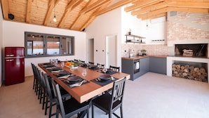 Eine moderne Küche mit einem langen Holztisch, gedeckt für das Essen, einem roten Kühlschrank und einem Kamin aus Ziegelsteinen.