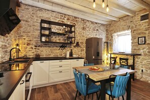 A rustic kitchen with stone walls, wooden beams, a central island with seating, and modern appliances. - Holiday Home Tranquilla With Heated Pool (Blato)