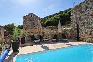 A stone building with a pool, lounge chairs, and umbrellas. - Holiday Home Tranquilla With Heated Pool (Blato)