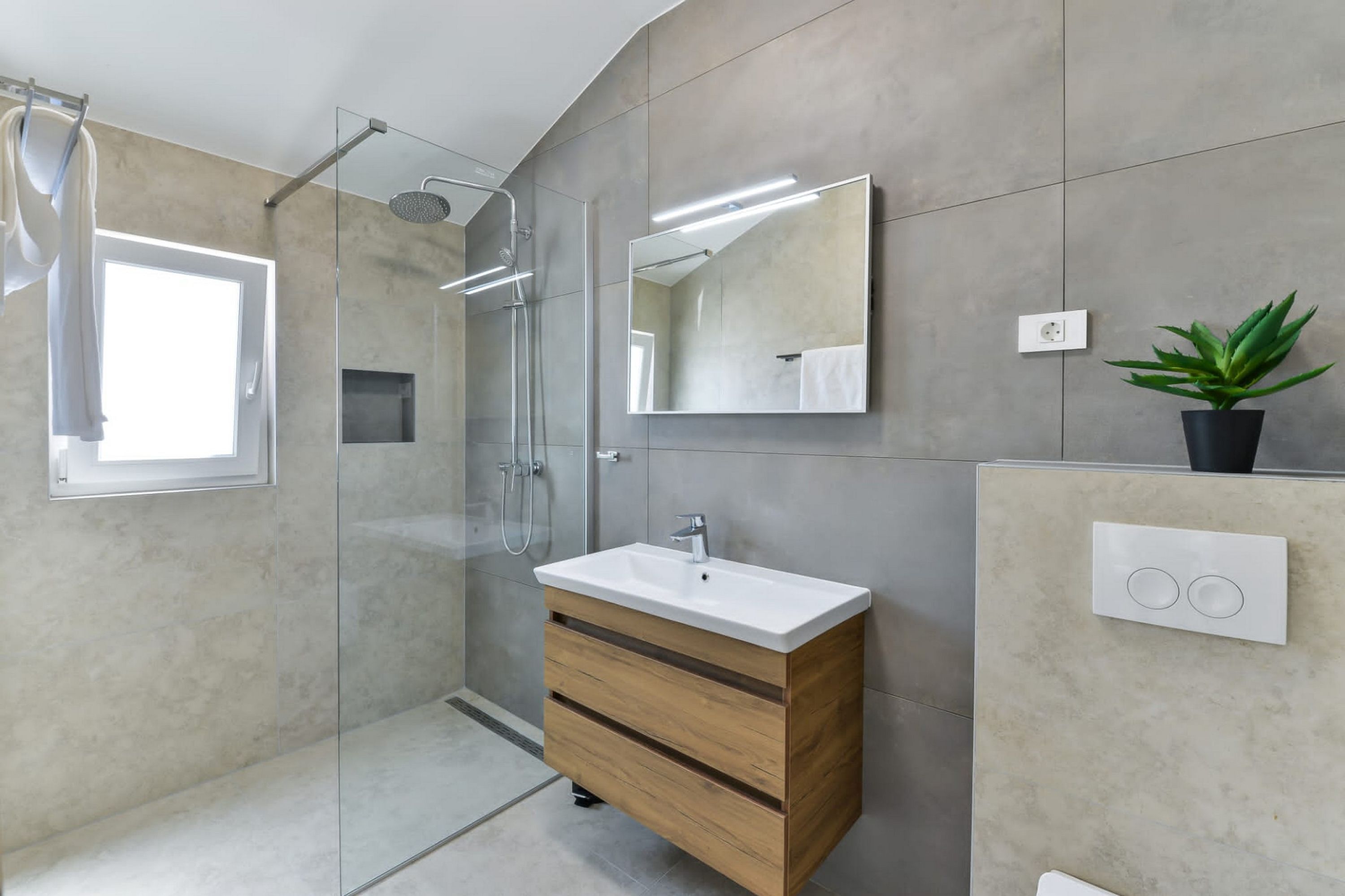 A modern bathroom with a glass-enclosed shower, a wooden vanity with a white sink, and a large mirror.