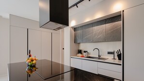 A modern kitchen with a black countertop, white cabinets, a marble backsplash, and a built-in oven. - Villa Kalea With Pool (Labin)